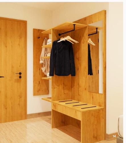 a room with a wooden closet with a black shirt hanging at Motel Sleep Inn in Töging am Inn