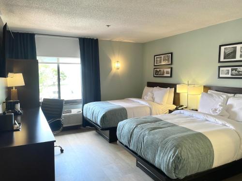 a hotel room with two beds and a desk at Wingate by Wyndham Salisbury in Salisbury