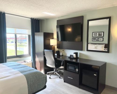 a hotel room with a bed and a desk with a television at Wingate by Wyndham Salisbury in Salisbury
