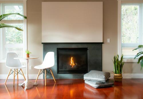 a living room with a fireplace and two white chairs at Welcome Home in North Vancouver