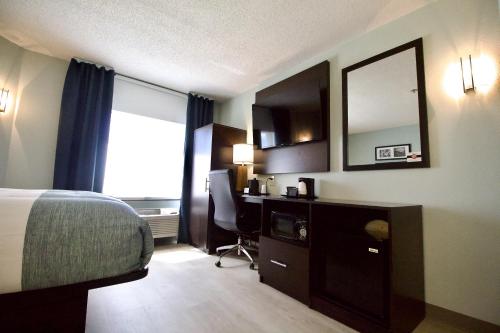 a hotel room with a bed and a desk and a mirror at Wingate by Wyndham Salisbury in Salisbury