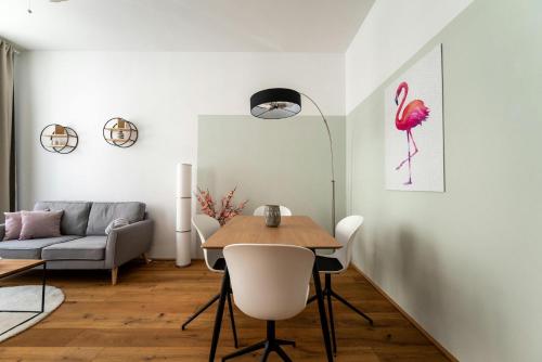 a living room with a table and a pink bird on the wall at Vrchol Holešovic Apartmány v Praze 7 in Prague