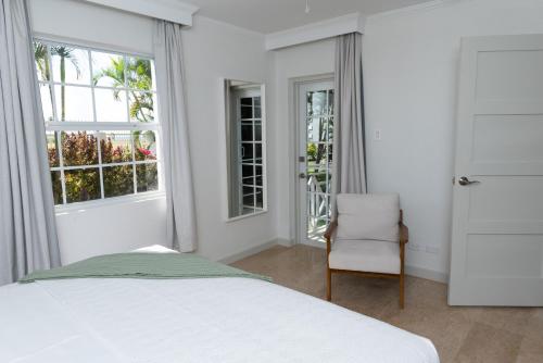 a bedroom with a bed and a chair and windows at South Point Hotel in Christ Church