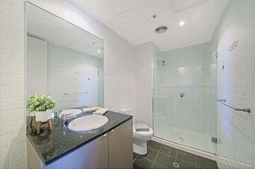 a bathroom with a sink and a shower and a toilet at A Comfy & Central 2BR Apt Near Flinders Station in Melbourne