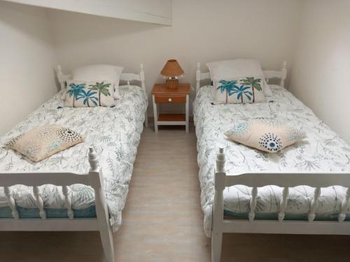 une chambre avec deux lits et une table avec une lampe dans l'établissement Maison de la mer, à Vaux-sur-Mer