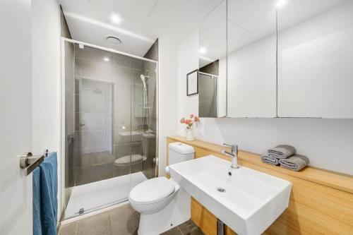 a white bathroom with a toilet and a sink at A Stylish 2BR CBD Apt with Beautiful City Views in Melbourne