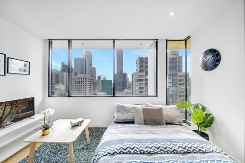 a bedroom with a bed and a large window at A Stylish 2BR CBD Apt with Beautiful City Views in Melbourne