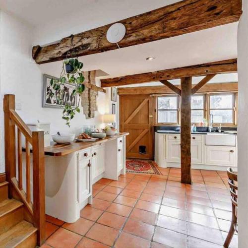 a large kitchen with white cabinets and wooden beams at Cosy luxury Grade II listed barn in the Forest of Dean in Westbury on Severn