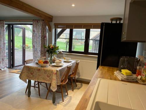 a kitchen with a table and chairs and a dining room at Cosy luxury Grade II listed barn in the Forest of Dean in Westbury on Severn