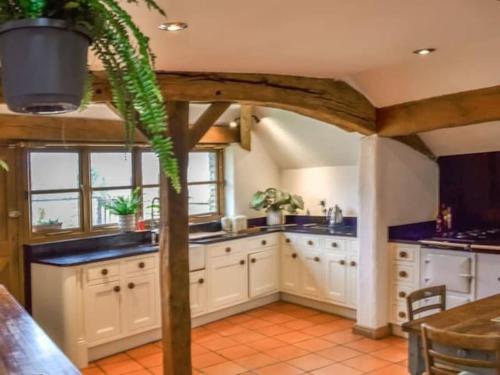a kitchen with white cabinets and a potted plant at Cosy luxury Grade II listed barn in the Forest of Dean in Westbury on Severn