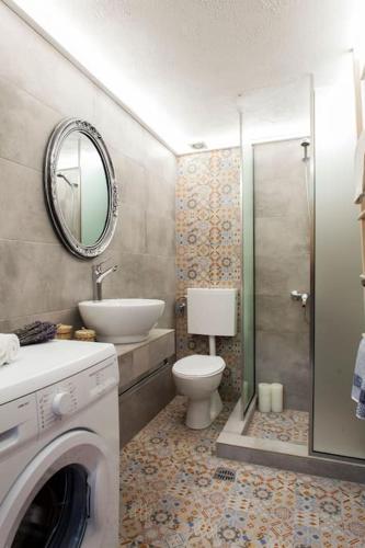 a bathroom with a toilet and a sink and a washing machine at Coastal Key 5 in Gázion
