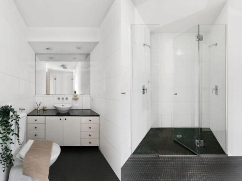 a white bathroom with a sink and a shower at A Modern & Cozy Studio Next to Darling Harbour in Sydney