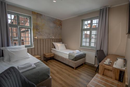 um quarto com 2 camas, uma secretária e 2 janelas em Soul House Gdansk Old Town em Gdansk