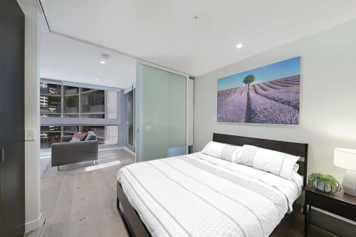 a bedroom with a large bed with a painting on the wall at A Bright & Modern CBD Apt Next to Southern Cross in Melbourne
