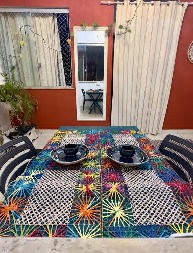 a table with plates on top of a colorful table cloth at Casa Lumen in Núcleo Bandeirante