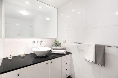 a white bathroom with a sink and a mirror at NEW! A Comfy & Stylish Apt Next to Darling Harbour in Sydney