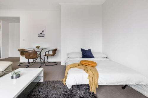 a white bedroom with a bed and a table at NEW! A Comfy & Stylish Apt Next to Darling Harbour in Sydney