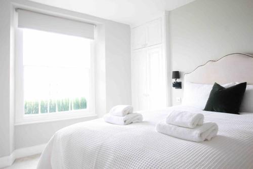 a white bedroom with a white bed with towels on it at Beautiful Top Floor Clifton Apartment in Bristol