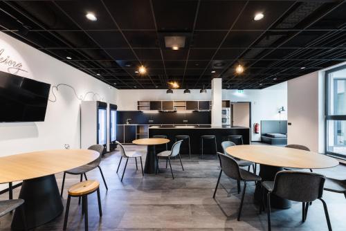 a room with tables and chairs and a kitchen at MoLiving - Design Hotel & Apartments Düsseldorf-Neuss in Neuss