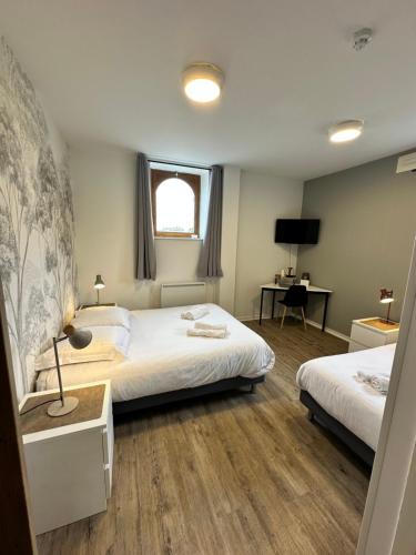 a hotel room with two beds and a desk at Hôtel Restaurant le clos de l 'Ancien Pressoir in Commes