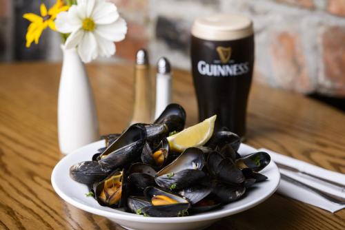 a plate of mussels on a table with a drink at Meadowlands Hotel in Tralee