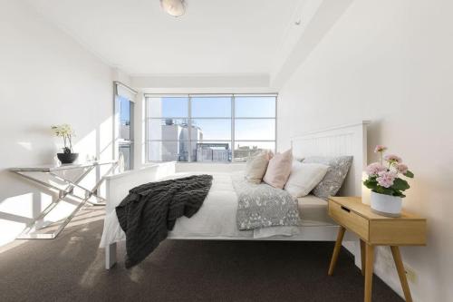 a white bedroom with a bed and a large window at A Spacious 2BR Apt with an Amazing View Over Darling Harbour in Sydney