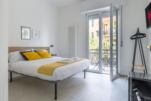 um quarto com uma cama com almofadas amarelas e uma varanda em Shiny Rooms Verona em Verona