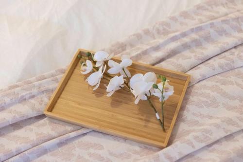 a wooden tray with white flowers on a bed at A Modern & Stylish Studio Next to Darling Harbour in Sydney
