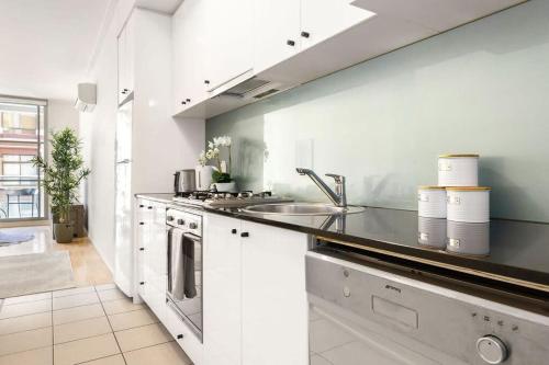 a white kitchen with a sink and a stove at A Modern & Stylish Studio Next to Darling Harbour in Sydney
