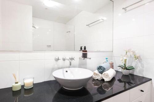 a white bathroom with a sink and a mirror at A Modern & Stylish Studio Next to Darling Harbour in Sydney