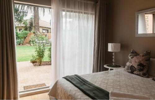 sypialnia z łóżkiem i dużymi przesuwnymi szklanymi drzwiami w obiekcie Zhantique Guest House Unit 5 w mieście Boksburg