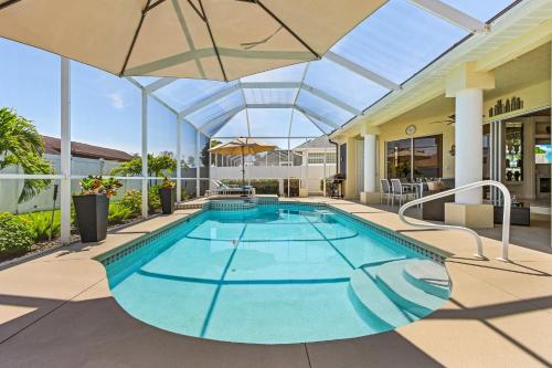 an indoor pool with an umbrella and a swimming pool at Villa-Haze, lots of privacy, solar & electric heated pool and SPA in Cape Coral