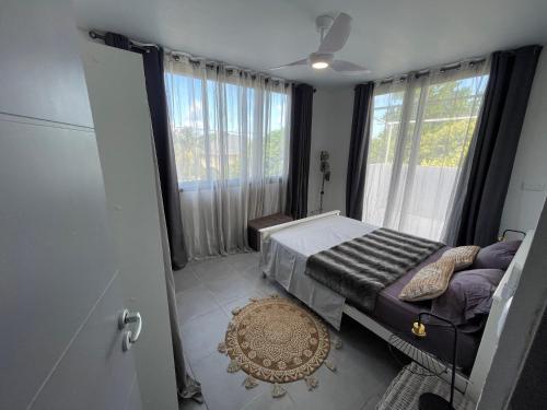 um quarto com uma cama e uma grande janela em Le Havre entre mer et forêt em Rémire-Camp