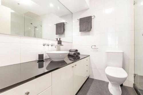 uma casa de banho branca com um lavatório e um WC em A Cozy & Modern Studio Right Next to Darling Harbour em Sydney