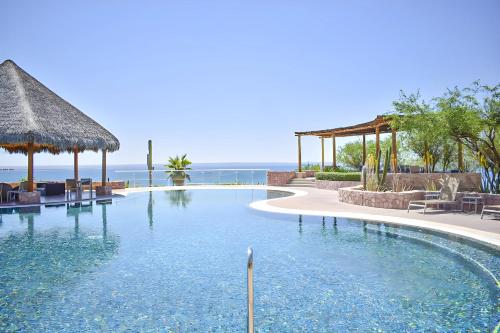 a swimming pool at a resort with the ocean in the background at Condo VistaMar in Puerta Cortes, Luxury 2BR 2Bath Condo Private beach & pool! in La Paz