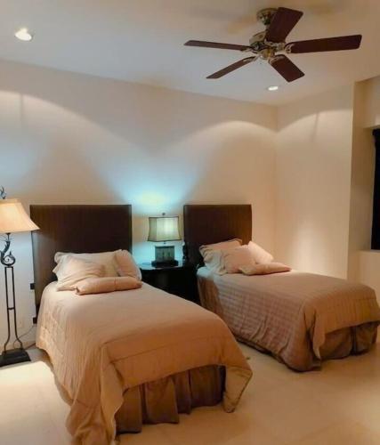 two beds in a bedroom with a ceiling fan at Condo VistaMar in Puerta Cortes, Luxury 2BR 2Bath Condo Private beach & pool! in La Paz