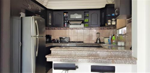 - une cuisine avec des armoires noires et un réfrigérateur blanc dans l'établissement Casa con piscina en urbanización privada, à Salinas
