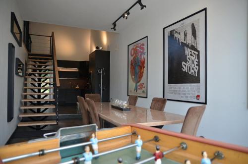 a dining room with a table and chairs and a staircase at Loft industriel dans une ancienne grange in Guenviller