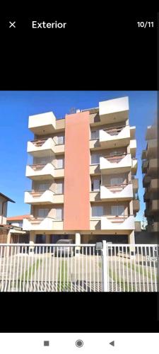 a tall apartment building in front of a white fence at Apartamento no Centro de Ubatuba in Ubatuba