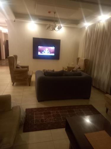 a living room with a couch and a flat screen tv at سهول الكرمل للشقق الفندقية in Amman