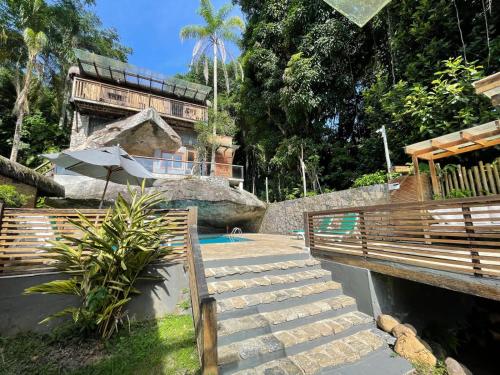 a resort with a swimming pool with stairs and an umbrella at Yannai Chalé Praia in Ilhabela