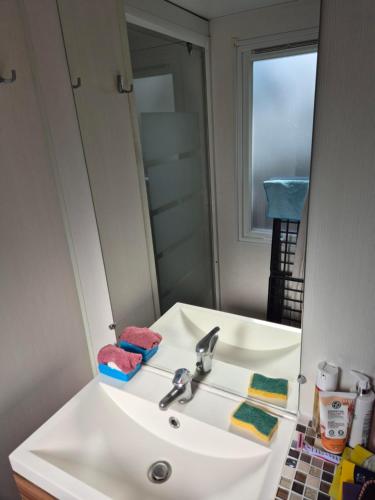 lavabo con espejo y lavabo blanco en Paisible camping les 7 fonds, en Agde