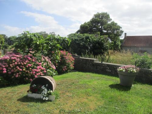 a garden with pink roses and a basket of flowers at GITE LE LILAS in Vierville-sur-Mer