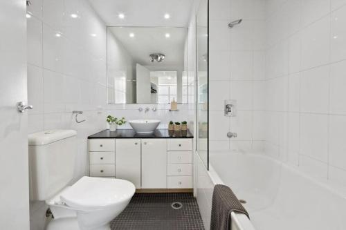 a white bathroom with a toilet and a sink at A Comfy 2BR Apt for 7 Next to Darling Harbour in Sydney