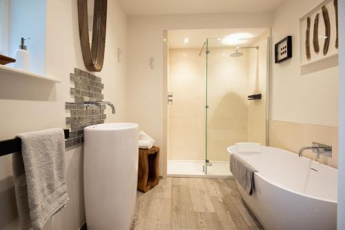 a white bathroom with a tub and a shower at The Old School in Edlingham