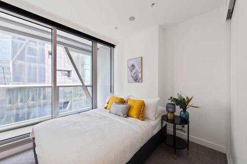 ein Schlafzimmer mit einem Bett und einem großen Fenster in der Unterkunft A Lux & Modern Apt Next to Southern Cross Station in Melbourne