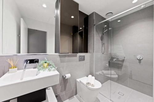 une salle de bain avec un lavabo, des toilettes et une douche dans l'établissement A Lux & Modern Apt Next to Southern Cross Station, à Melbourne