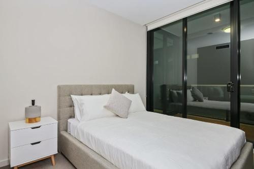1 dormitorio con cama blanca y ventana en A Comfy Albert Park Apt Next to Grand Prix Circuit en Melbourne