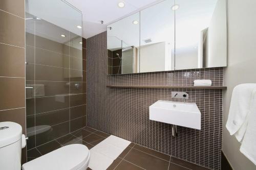een badkamer met een toilet, een wastafel en een spiegel bij A Comfy Albert Park Apt Next to Grand Prix Circuit in Melbourne