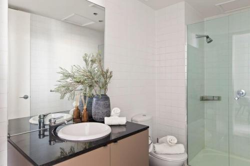 a bathroom with a sink and a glass shower at A Cozy 2BR Apt on Collins Near Flinders Station in Melbourne